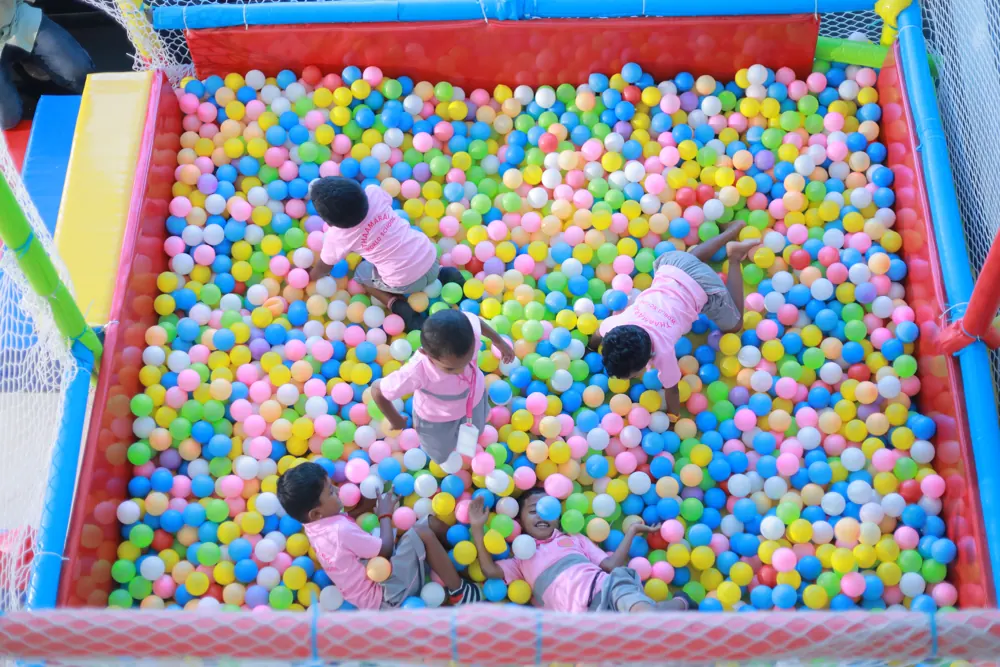 Young children play in a pit of coloured balls