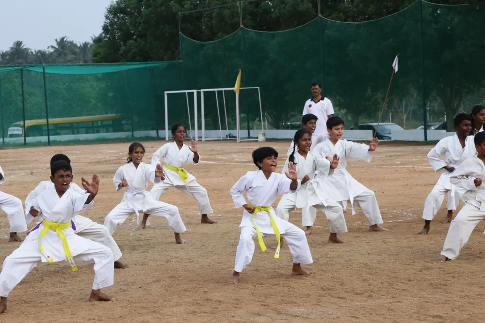 Students in white karate uniforms practise on the field