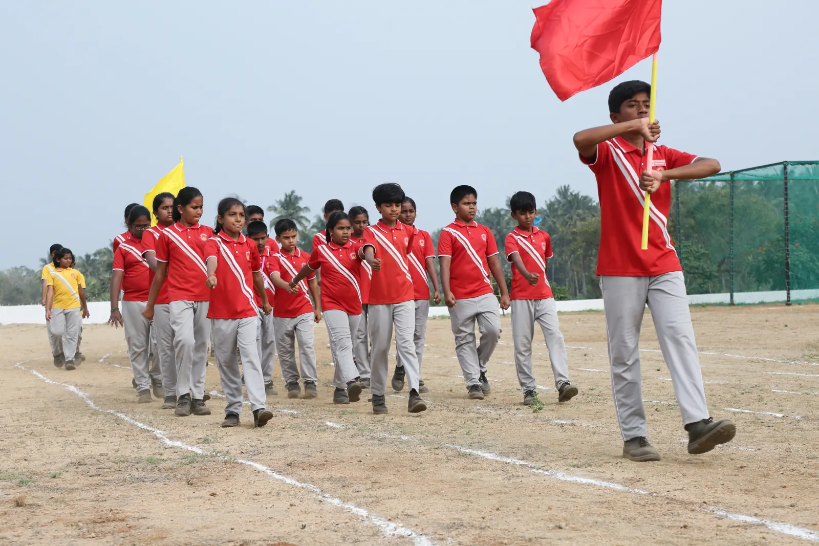 A student carries a red flag at the head of his house’s march past on sports day