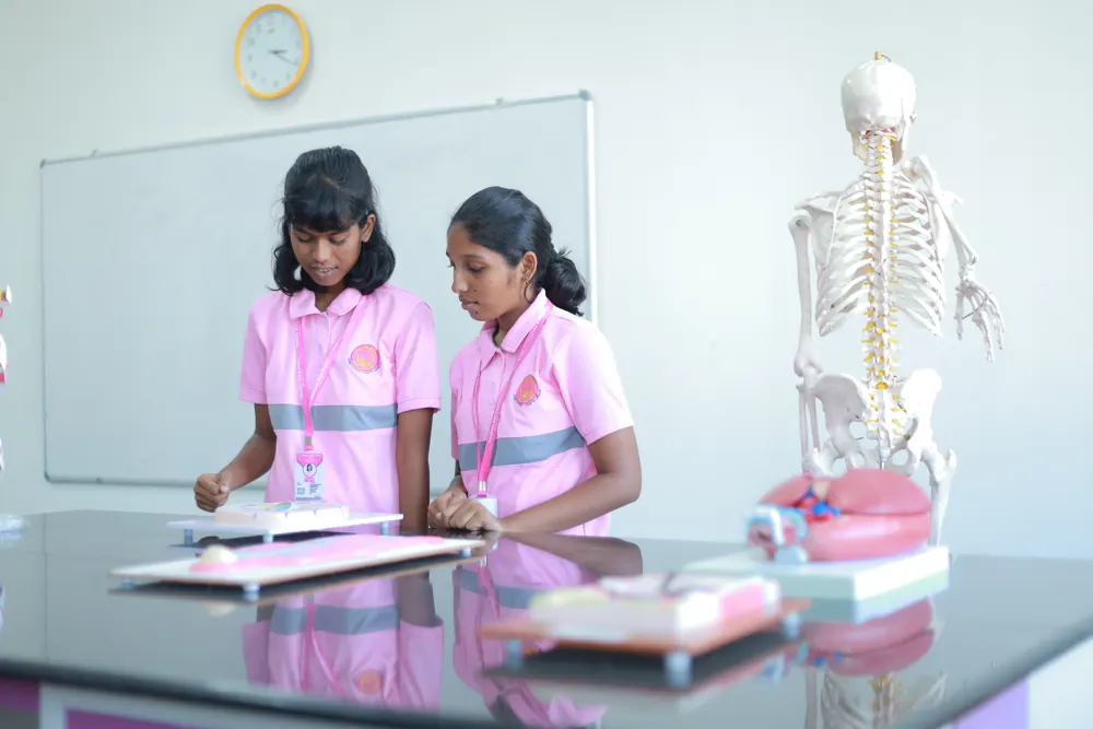 Two girls study beside a model skeleton in the biology lab